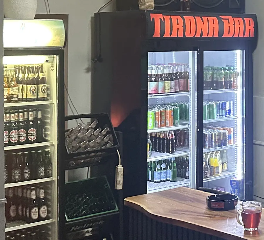 Kühlschränke der Tirona Bar mit Flaschenbier und Softdrinks, oben der Schriftzug Tirona Bar