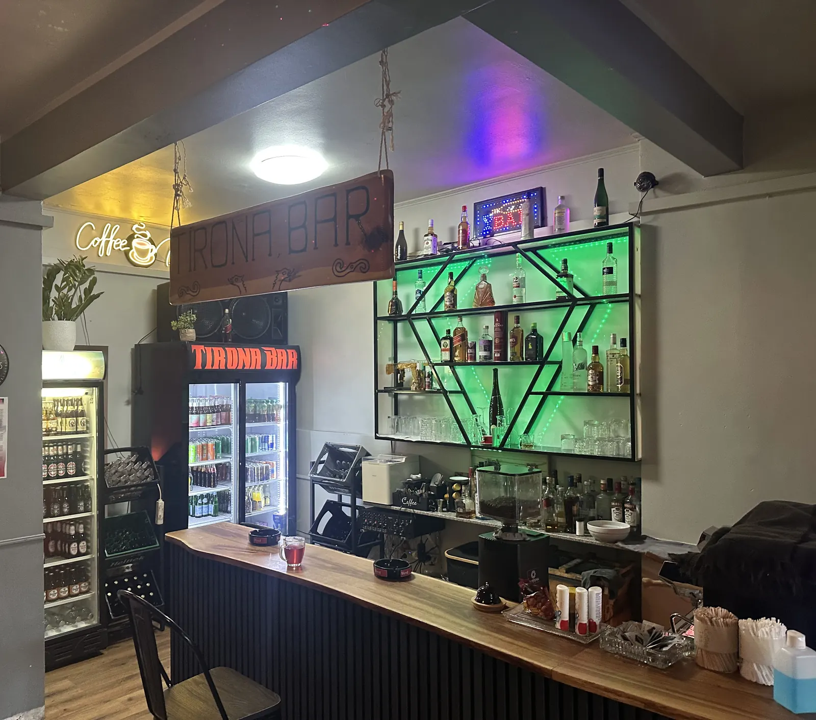 Holztheke der Tirona Bar mit grün beleuchtetem Flaschenregal und Kühlschrank mit Tirona-Schriftzug